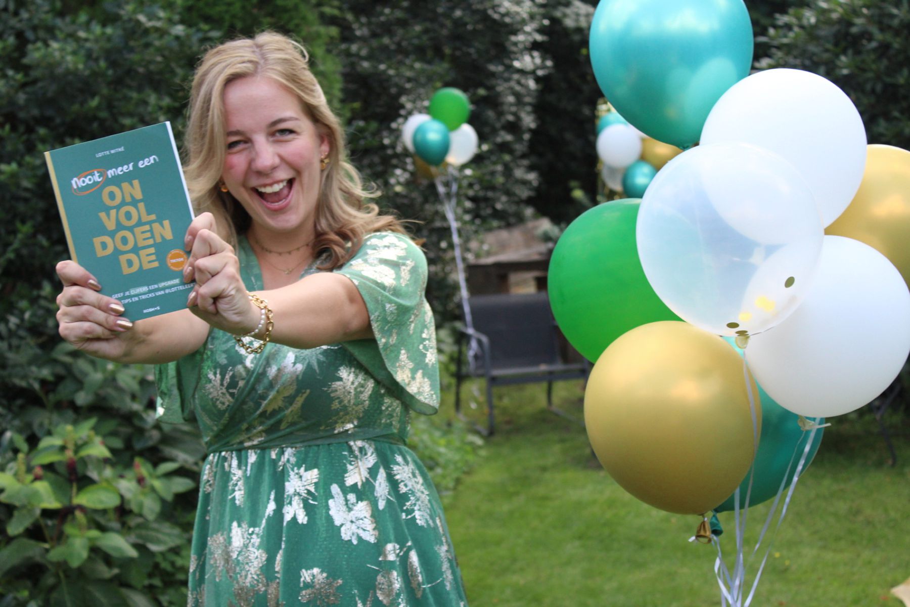 Lotte houdt blij haar boek Nooit meer een onvoldoende omhoog, tussen de ballonnen